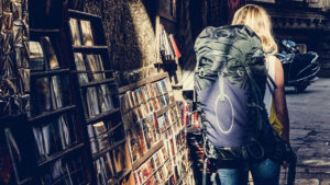 writers block tips - image of a backpacker passing a bookshelf on the street